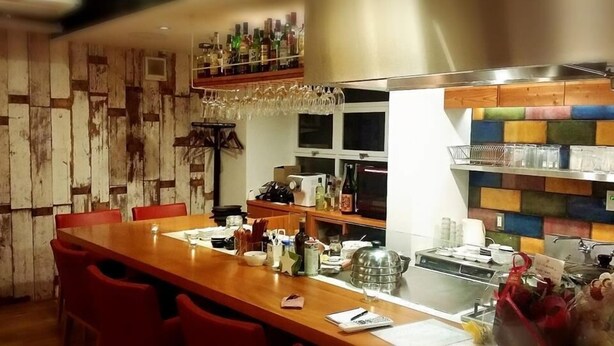 A restaurant with a wooden table, red chairs, a bar area with bottles and glasses, and a colorful wall. - New Minka Guest House (Tokyo)
