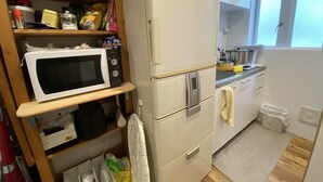 A compact kitchen with a microwave, refrigerator, and a small countertop. - New Minka Guest House (Tokyo)