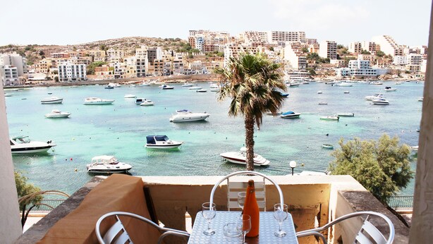 A balcony with a table and chairs overlooking a marina with boats. - Blue Harbour 1 Seafront Holiday 2-bedroom Apartment With Terrace St Pauls Bay (St. Paul's Bay)