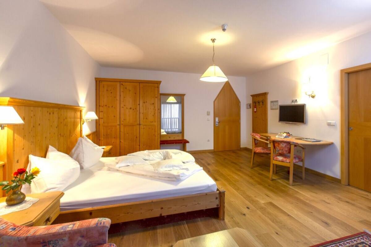 Un dormitorio con una cama de madera, mesitas de noche, un escritorio, una silla y un televisor.