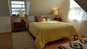 Een slaapkamer met een bed, twee nachtkastjes, een raam en uitzicht op de omgeving.
