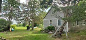 Een huis met een schuin dak en een voortuin met een veranda.