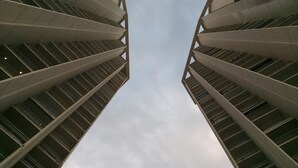 Ein hoch aufragendes Gebäude mit symmetrischer Gestaltung, das mehrere Balkone und eine zentrale, nach oben gerichtete Perspektive aufweist.