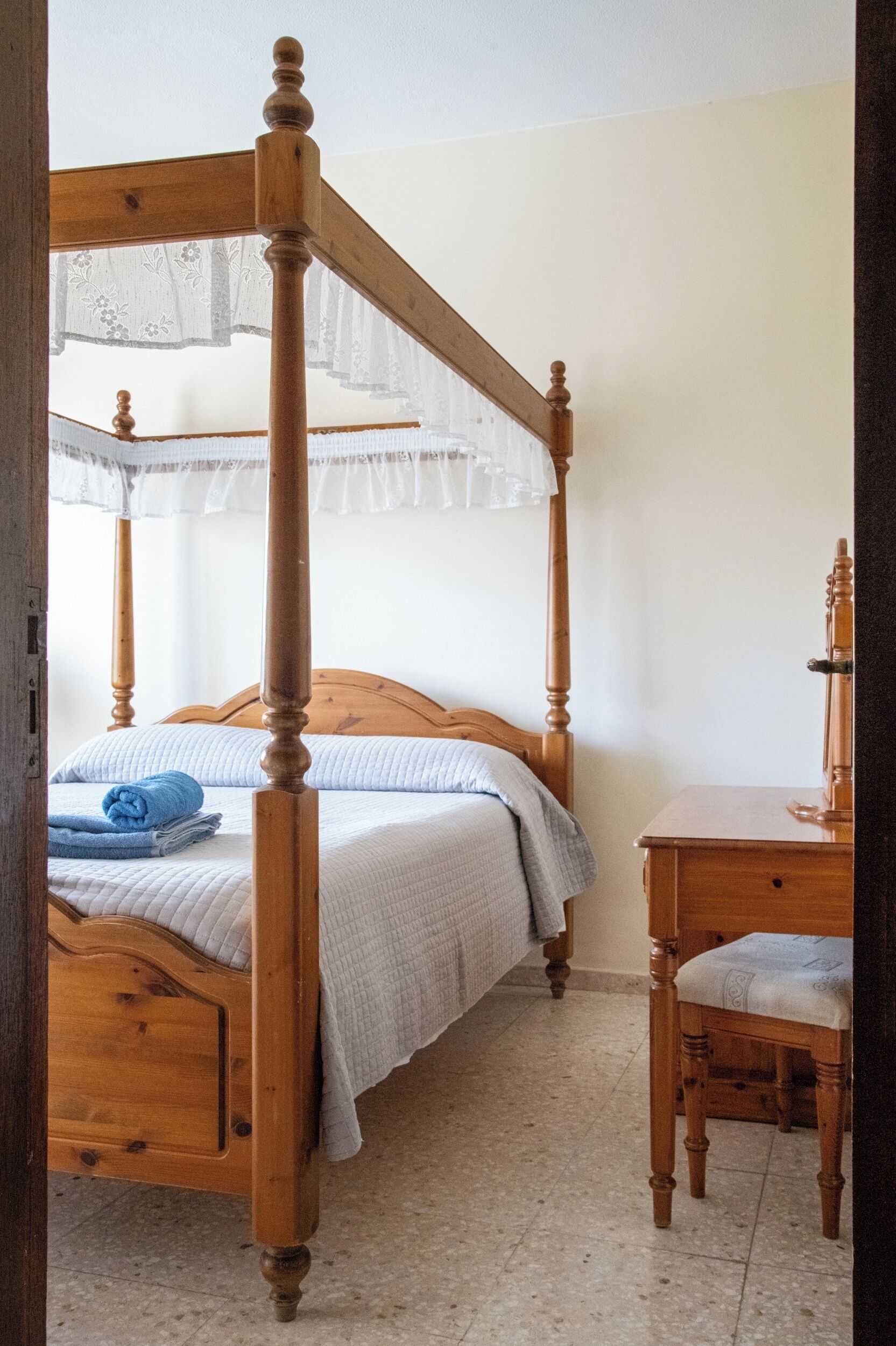 Una cama con dosel, una mesita de noche de madera y una silla.