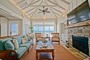 A spacious living room with a high ceiling, a fireplace, and a view of the ocean. - Cinnamon Sands 6 Bedroom Home by RedAwning (Supply)