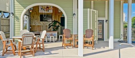 Ein Poolbereich mit Adirondack-Stühlen und einer überdachten Terrasse.
