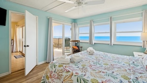 A room with a bed, a ceiling fan, a view of the ocean, and a door leading to a balcony. - Oceanfront Beach Condo with Private Balcony, Short Walk to Pool and Beach by RedAwning (Fernandina Beach)