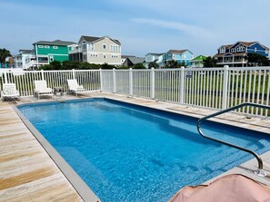 Relax by the pool surrounded by comfortable lounge chairs and a fenced area.