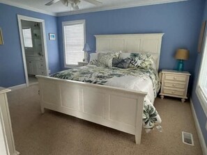 Relax in this serene bedroom with a four-poster bed, nightstand, and ceiling fan.