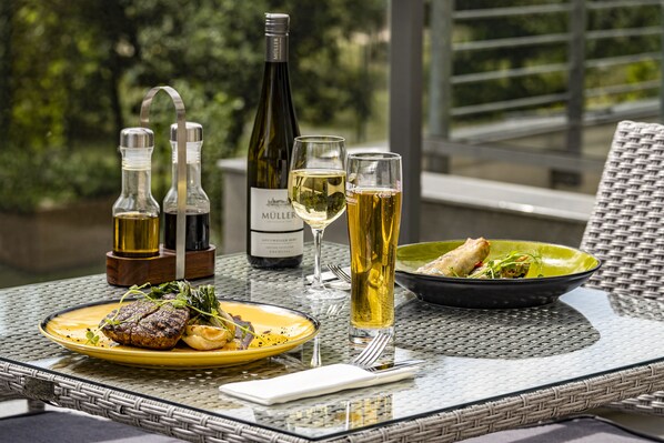 Uma mesa de jantar com uma garrafa de vinho, duas taças, uma saladeira e um prato de comida.
