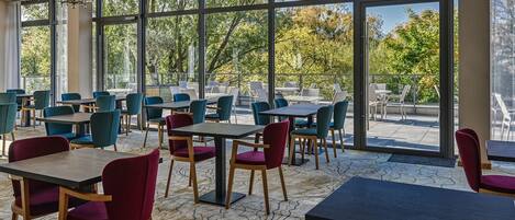 Un comedor moderno con amplios ventanales, mesas y sillas.