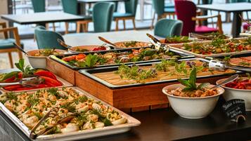 Una mesa de buffet con diversos platos, incluyendo mariscos y ensaladas, dispuestos en bandejas y tazones.