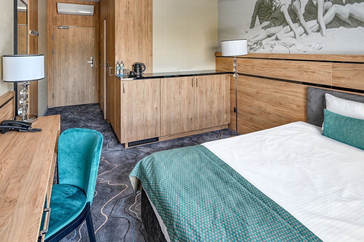 Una habitación de hotel con cama, escritorio, silla, minibar y baño.