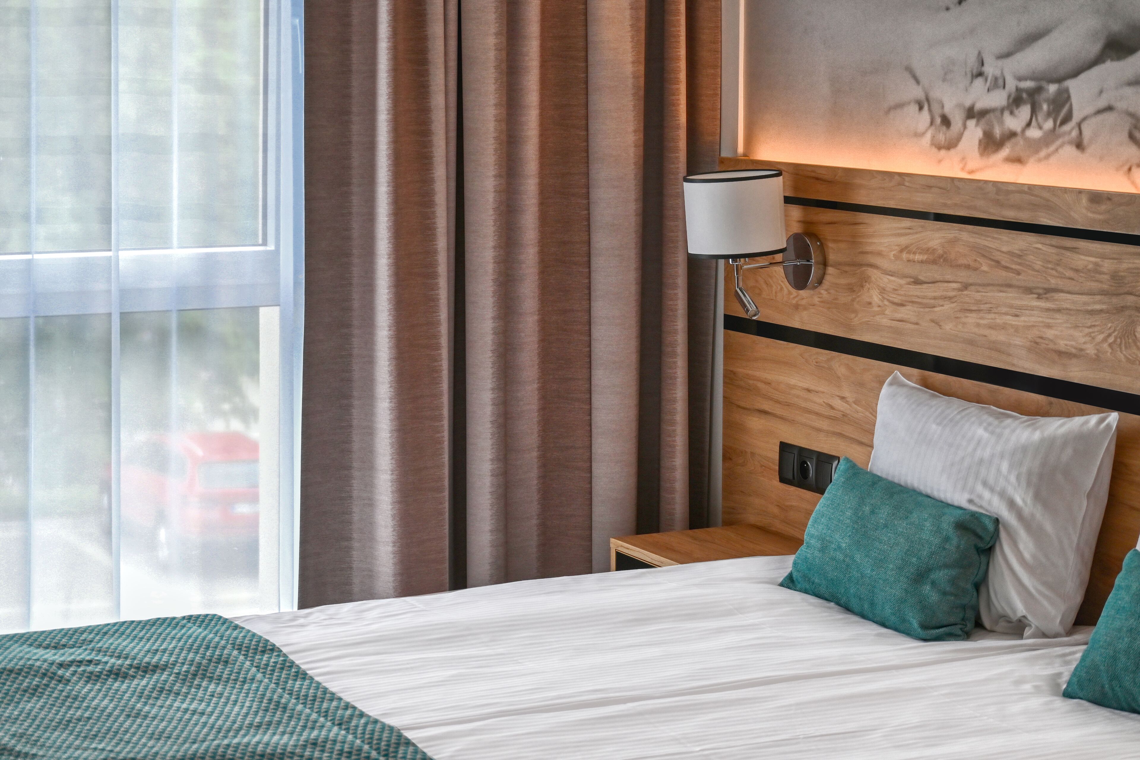 A hotel room with a large bed, a nightstand, a lamp, and a painting on the wall.
