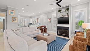 Uma sala de estar moderna com sofá modular, lareira, televisão e área de jantar.