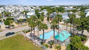 A residential area with a swimming pool surrounded by palm trees and houses. - Island in The Sun (Destin)
