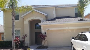 A two-story house with a garage, a driveway, and a white car parked in front.