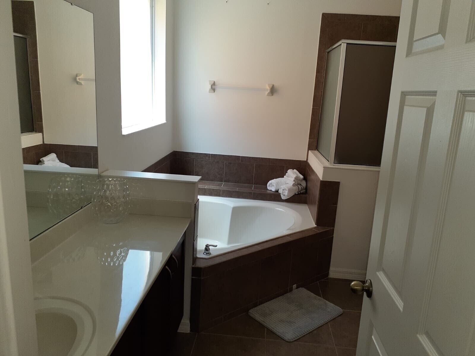 A bathroom with a bathtub, a vanity with a mirror, and a towel rack.