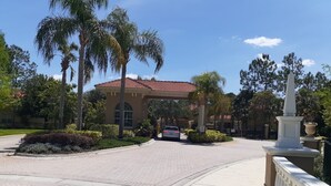 A building with a red-tiled roof, surrounded by palm trees and a paved walkway.