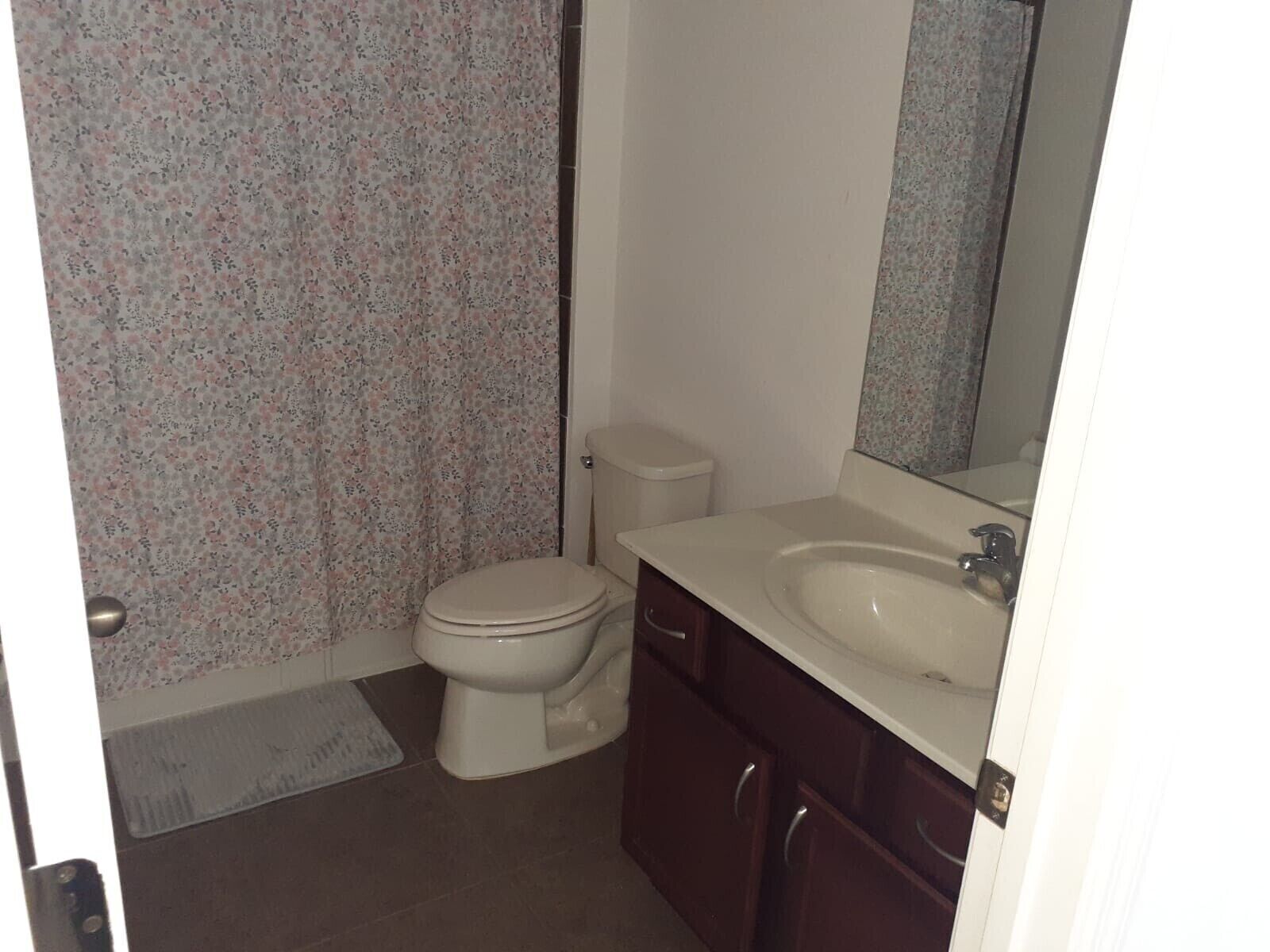 A bathroom with a toilet, sink, and mirror.