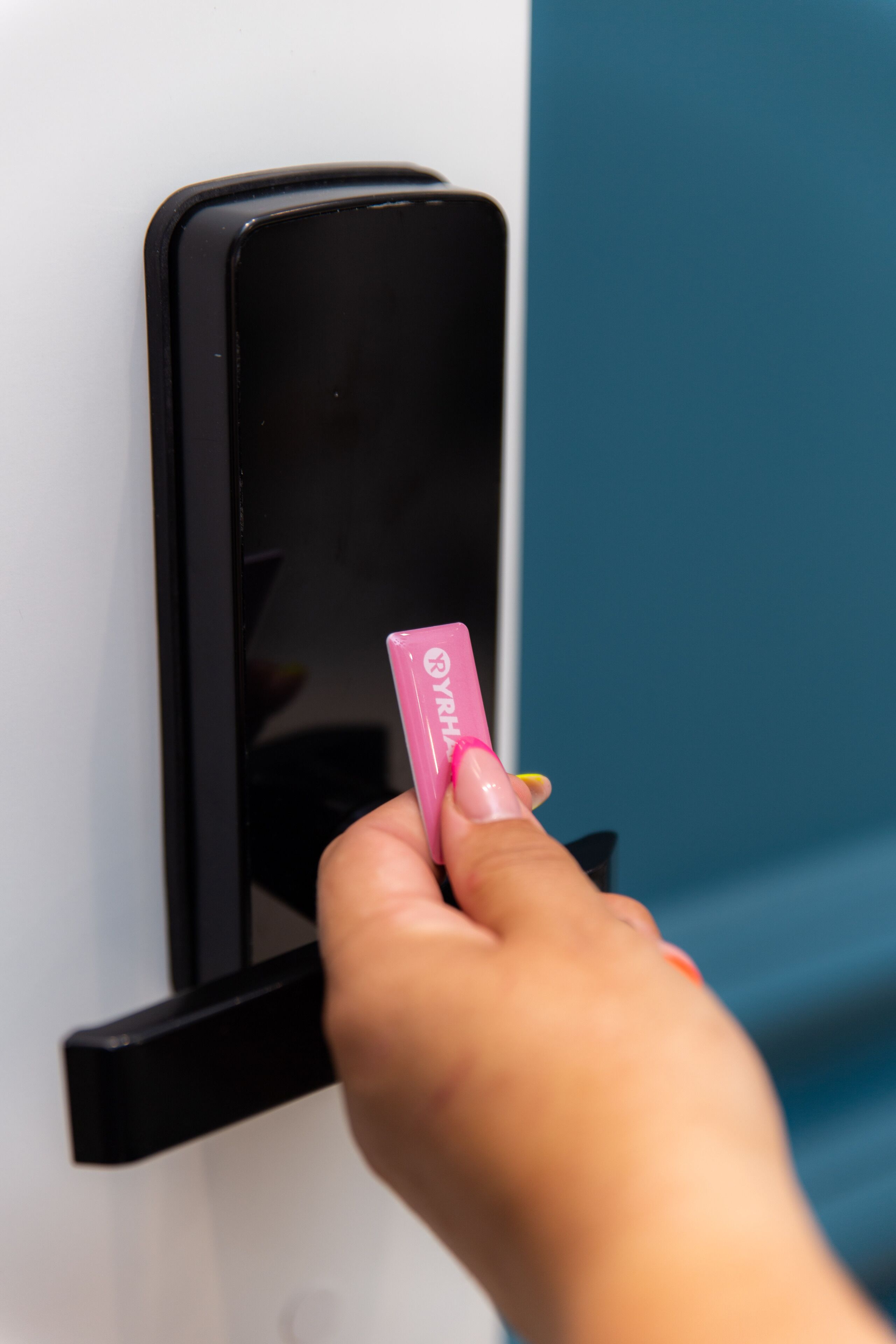 Una mano insertando una tarjeta rosa en una ranura negra en una pared blanca y azul.