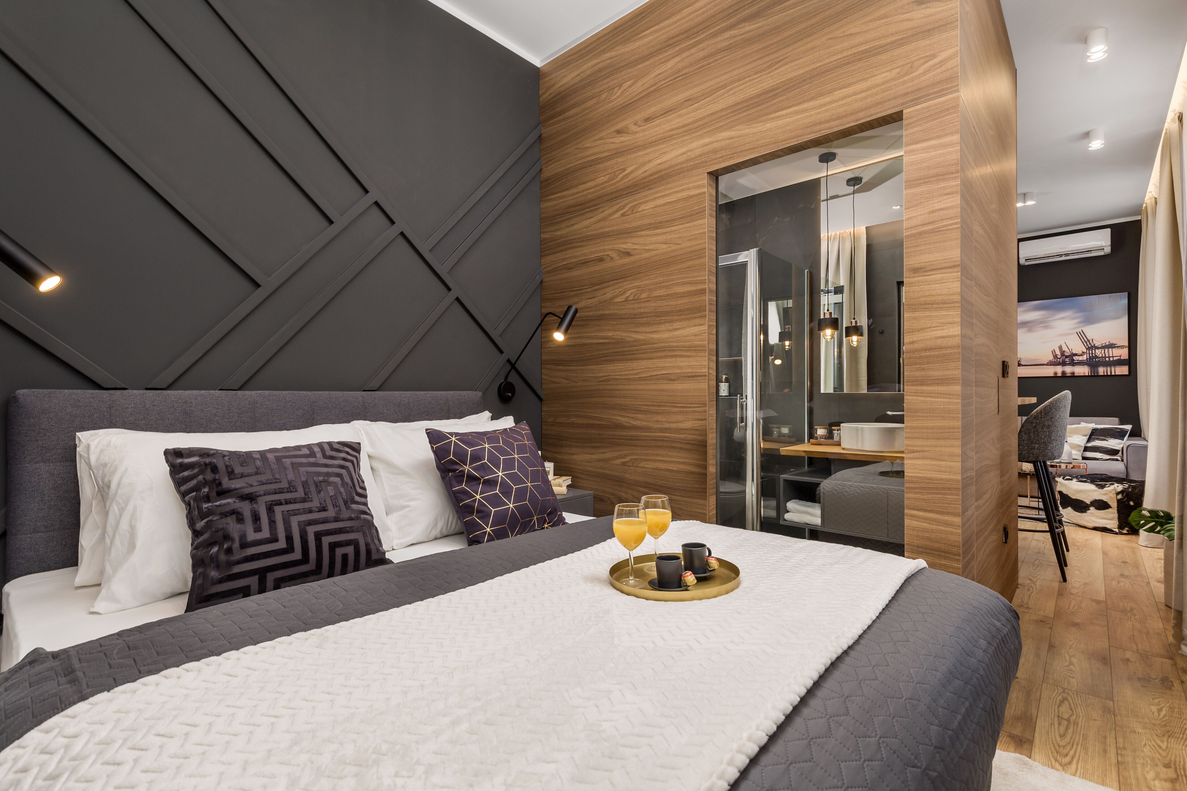 Una habitación de hotel moderna con una cama grande, un panel decorativo de madera y un box de ducha de vidrio.