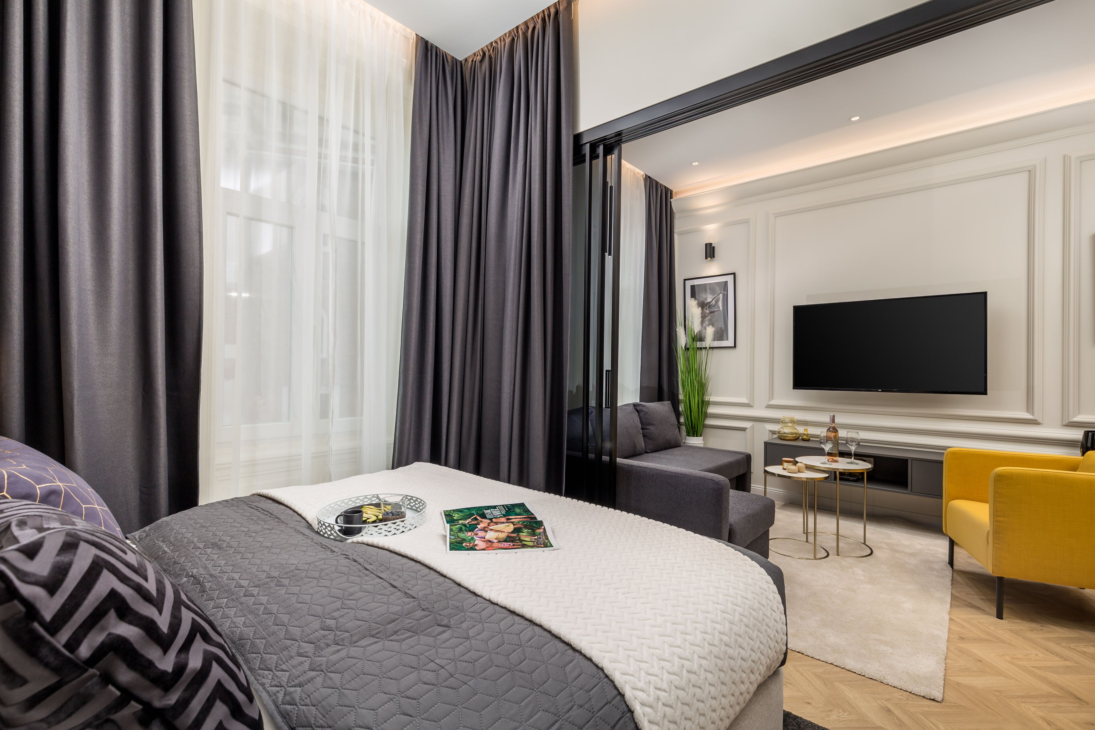 Una habitación de hotel moderna con una cama grande, un televisor de pantalla plana, un sofá y una pequeña mesita.