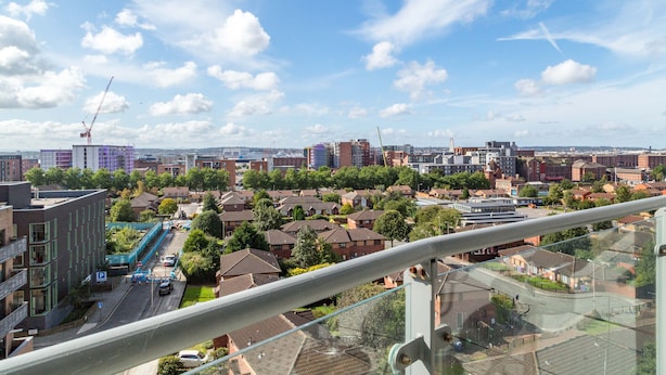 A high-rise building with a view of a cityscape, including residential areas and a construction site.