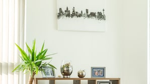 A modern living room with a wooden console table, a potted plant, and a grey sofa.