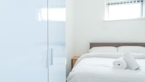 A hotel room with a bed, a nightstand, and a window.
