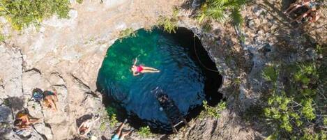 A circular natural pool surrounded by rocky terrain and sparse vegetation.