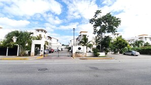 A gated residential area with white buildings, a central gate, and a palm tree. - Nice Apartment & Pool in Playa del Carmen 8 Min From the Caribbean Sea (Playa del Carmen)