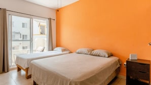 A room with two beds, a window, and a view of buildings outside. - Nice Apartment & Pool in Playa del Carmen 8 Min From the Caribbean Sea (Playa del Carmen)