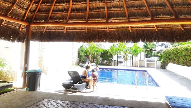 A thatched-roof outdoor area with a pool, lounge chairs, and a trash bin. - Nice Apartment & Pool in Playa del Carmen 8 Min From the Caribbean Sea (Playa del Carmen)