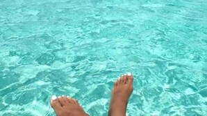 Piedi in acqua cristallina turchese, che suggerisce una spiaggia o un bordo piscina.