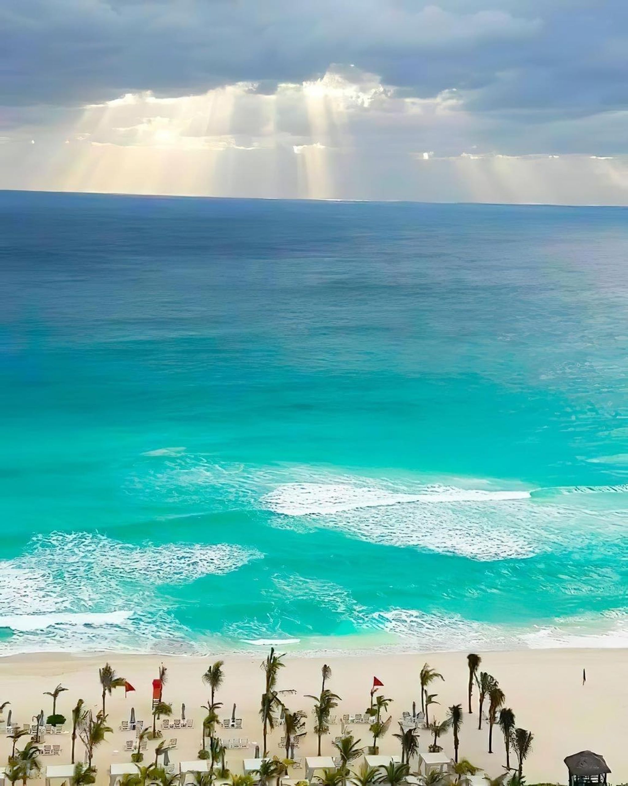 A beach with clear turquoise waters, palm trees, and a view of the ocean.