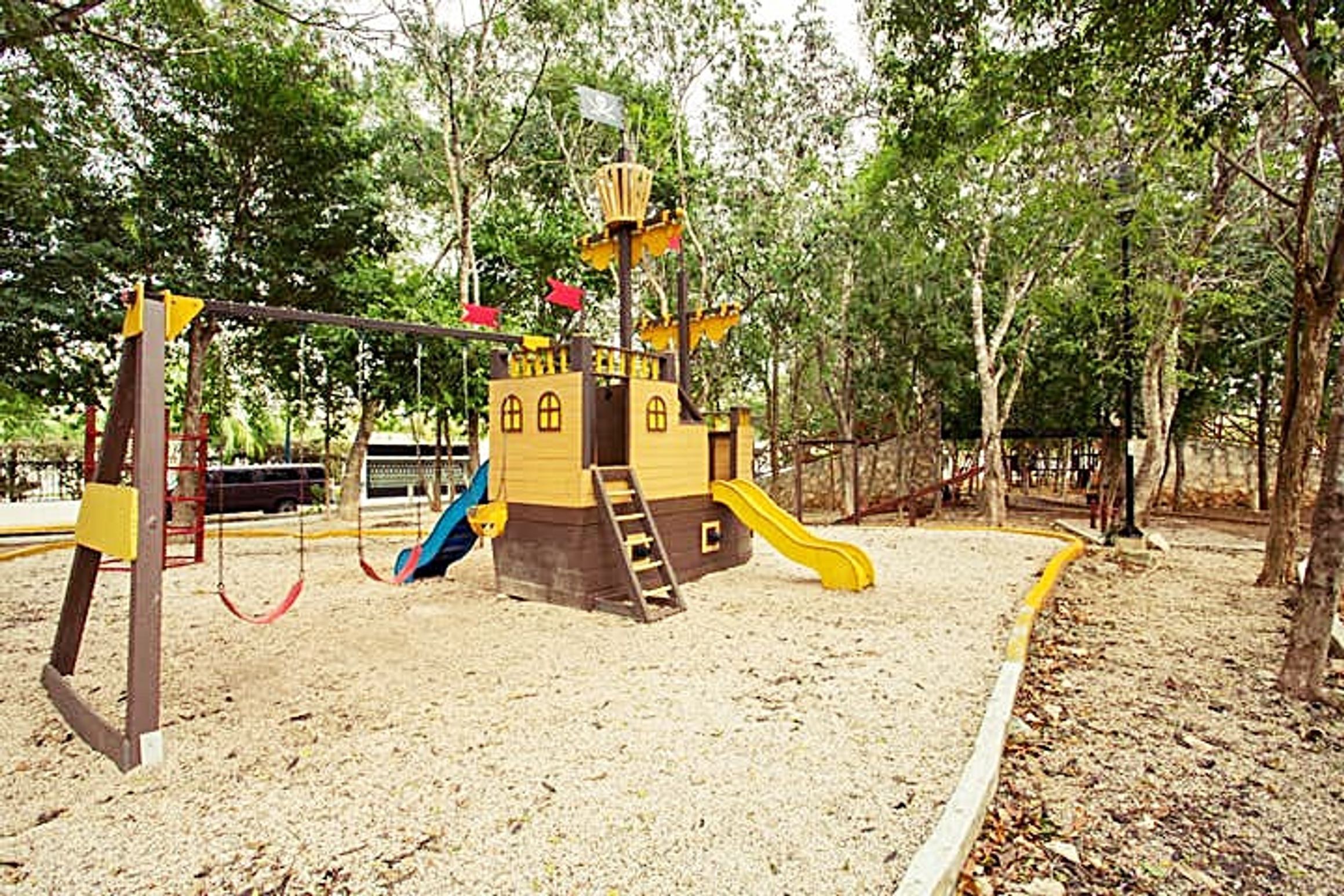 A playground with a castle-like structure, swings, and slides.