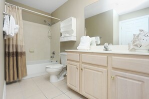 A bathroom with a bathtub, toilet, and vanity with a mirror. - Ocean Villa 2305 (Panama City Beach)