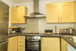 Een moderne keuken met houten kastjes, roestvrijstalen apparatuur en een betegelde achterwand.