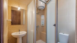 A bathroom with a shower, sink, toilet, and a mirror.