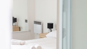 A modern bedroom with a bed, bedside tables, a mirror, and a hanging light fixture. - Kent Street - Apt 4 (Liverpool)