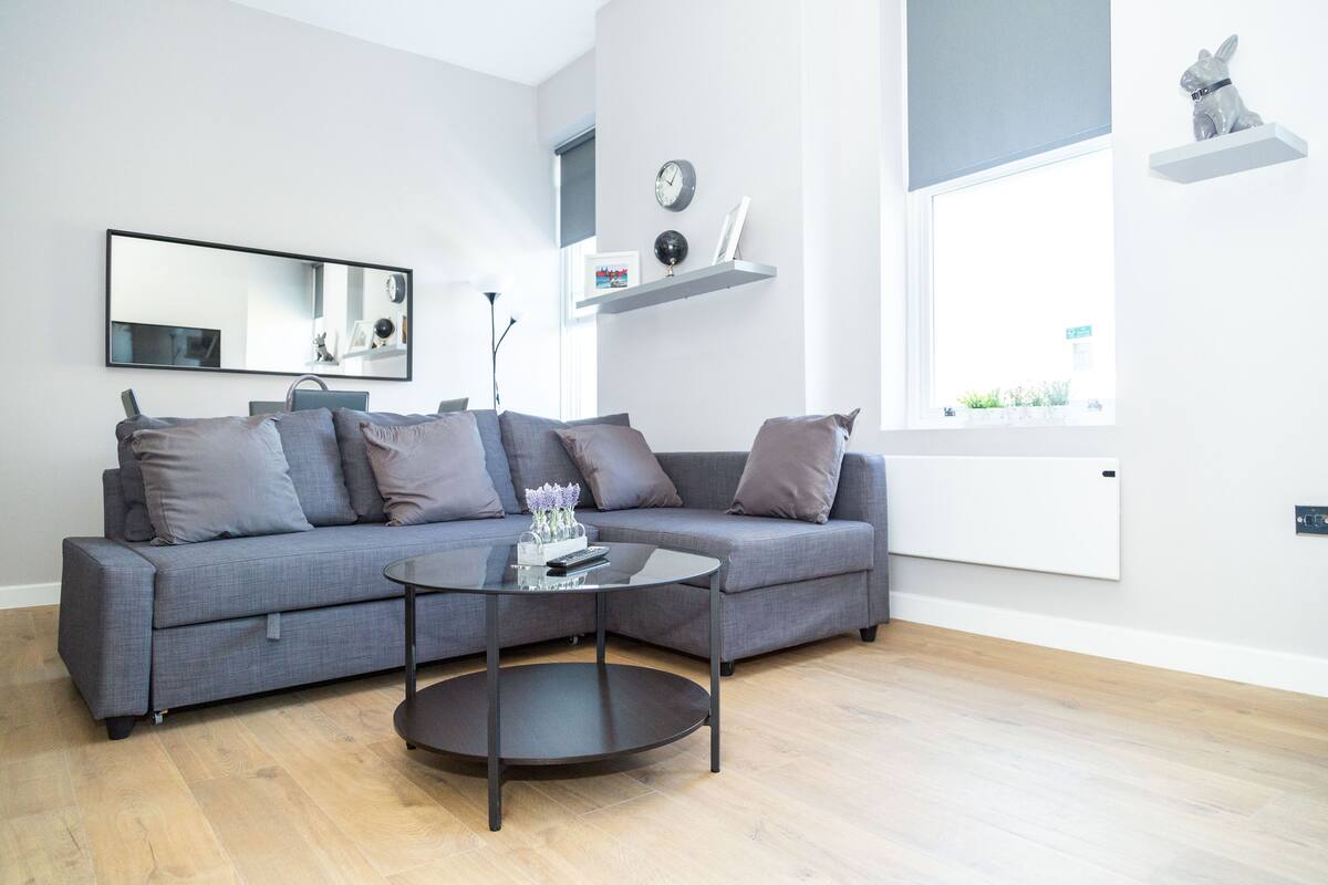 A modern living room with a grey sofa, a round coffee table, and a large window.