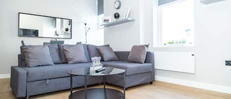 A modern living room with a grey sofa, a round coffee table, and a large window.