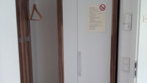 A narrow hallway with a white wardrobe, a wooden shelf unit, and a white mat on the floor. - On the Allgäu cycle path, quiet apartment, with bicycle garage (Lachen-Hetzlinshofen)
