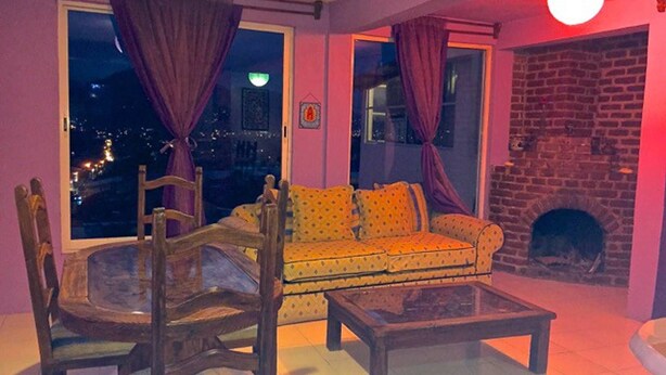 A living room with a sofa, a wooden chair, a coffee table, and a fireplace. - Lindo Depa Chimenea Preciosa Vista (San Cristóbal de las Casas)