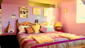 A bedroom with a bed, nightstands, a lamp, and wall decorations. - Lindo Depa Chimenea Preciosa Vista (San Cristóbal de las Casas)