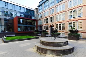 A courtyard with a circular brick platform, benches, and planters with greenery. - Temple Lane (Liverpool)