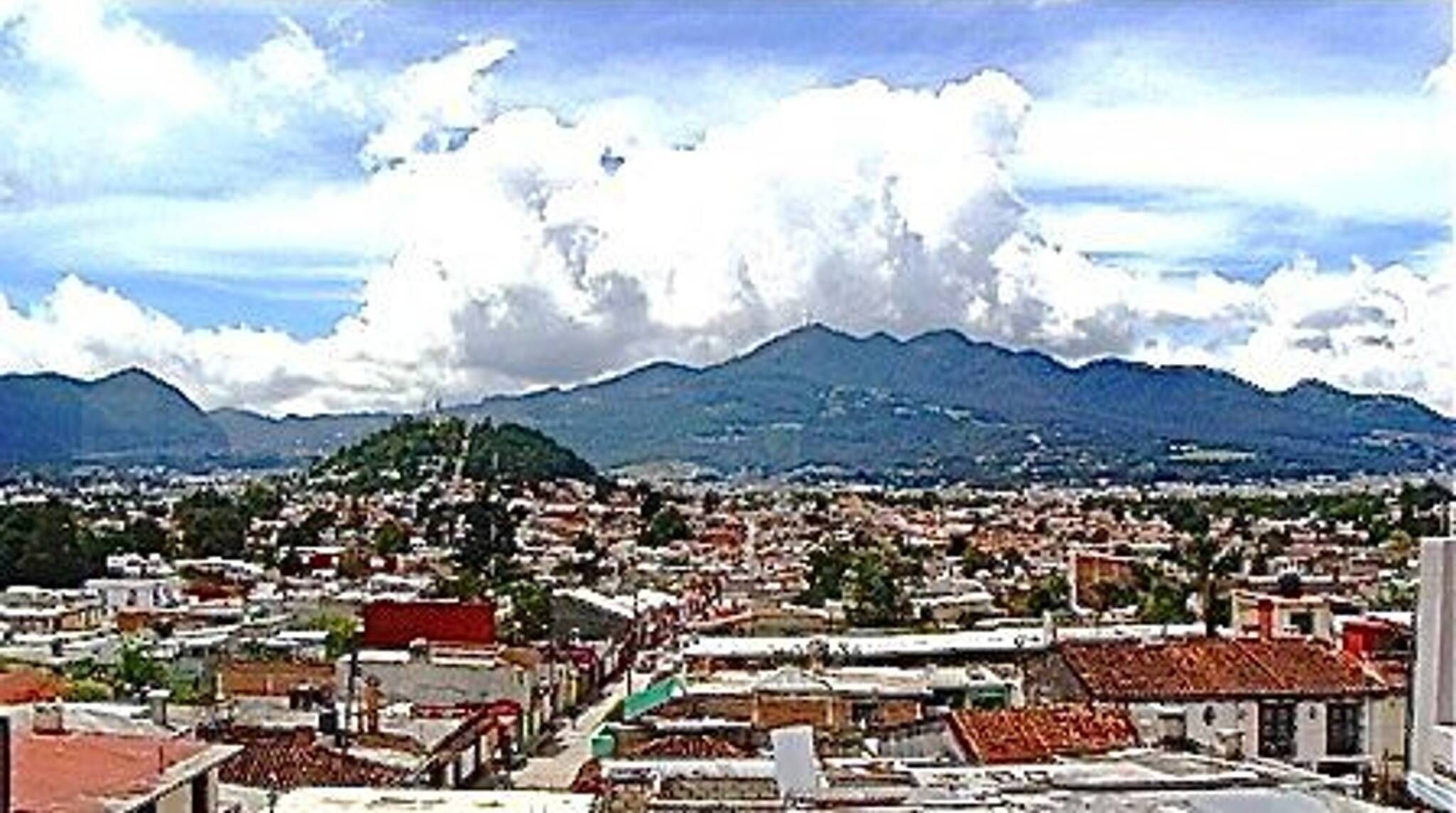 Un paisaje urbano con una cadena montañosa al fondo.