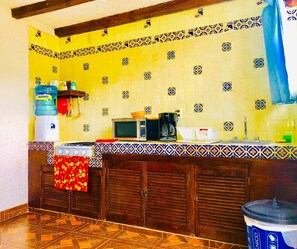 A kitchen with yellow tiled walls, a gas stove, a microwave, and a sink. - Comfy 4 Bedroom Town House Garden Market Area (San Cristóbal de las Casas)