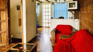 A room with a wooden door, a television mounted on the wall, and a red sofa. - Comfy Bedroom Town House Garden Market Area (San Cristóbal de las Casas)